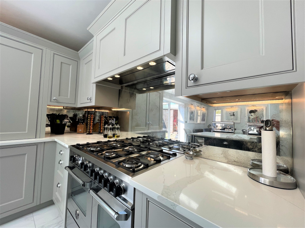 Photo of a mid-sized traditional l-shaped eat-in kitchen in Other with raised-panel cabinets, medium wood cabinets, quartz benchtops, glass sheet splashback, stainless steel appliances, porcelain floors and with island.