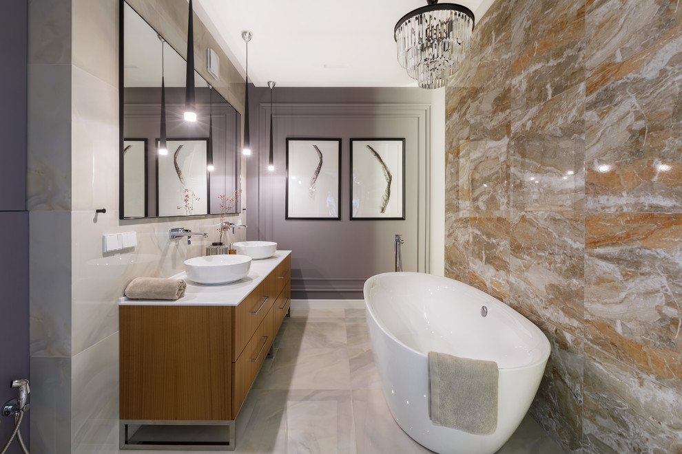 Photo of a contemporary master bathroom in Yekaterinburg with flat-panel cabinets, medium wood cabinets, a freestanding tub, beige tile, grey walls, a vessel sink, grey floor and white benchtops.