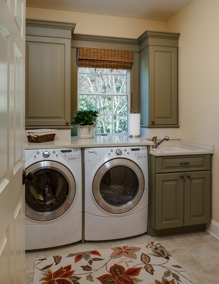 This is an example of a traditional laundry room in Baltimore with an undermount sink, raised-panel cabinets, green cabinets, beige walls, a side-by-side washer and dryer, beige floor and beige benchtop.