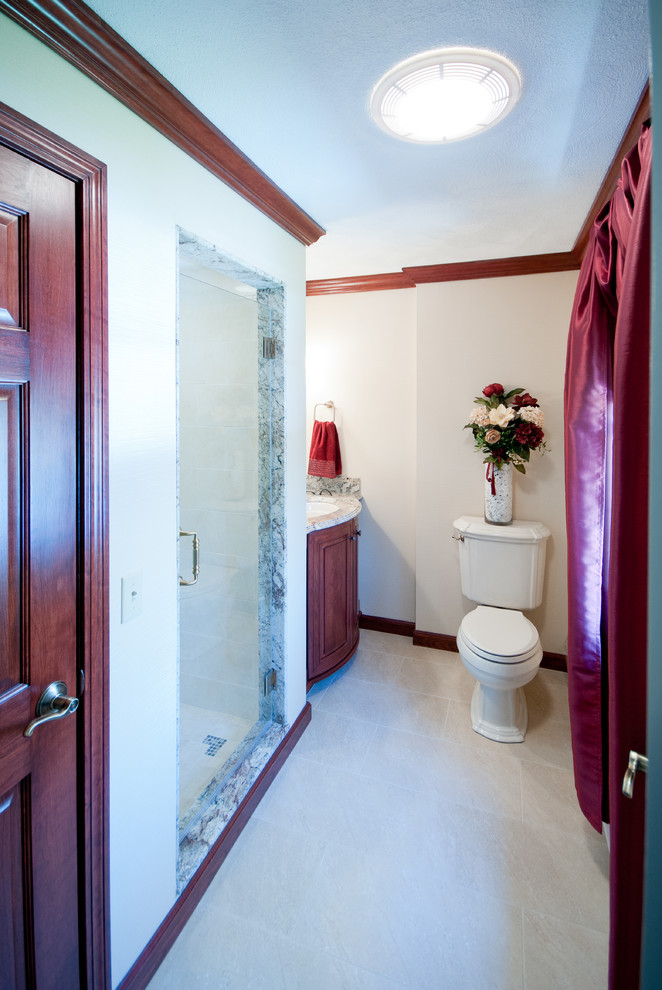 Inspiration for a mid-sized traditional master bathroom in Providence with furniture-like cabinets, medium wood cabinets, granite benchtops, beige tile, ceramic tile, an alcove shower, a two-piece toilet, an undermount sink, beige walls and porcelain floors.