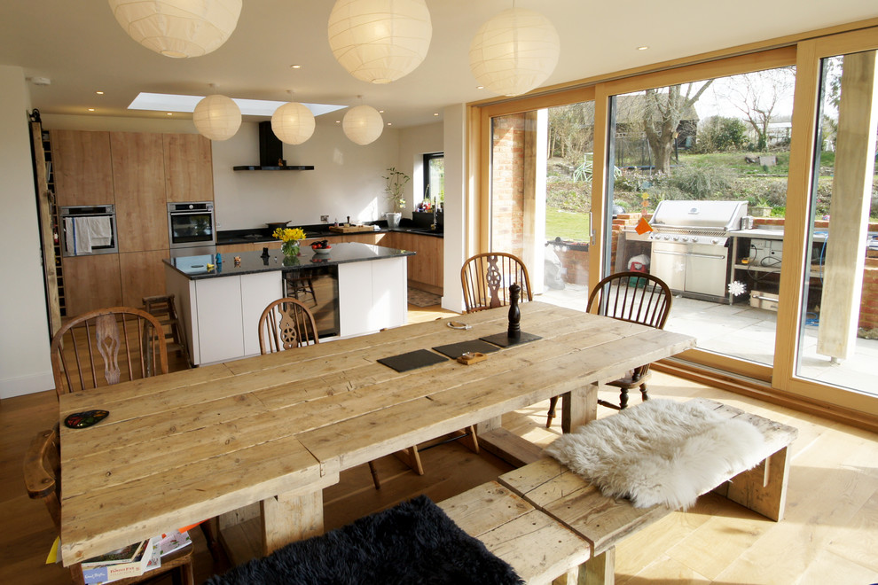 Inspiration for a mid-sized country kitchen/dining combo in Dorset with white walls, medium hardwood floors and brown floor.
