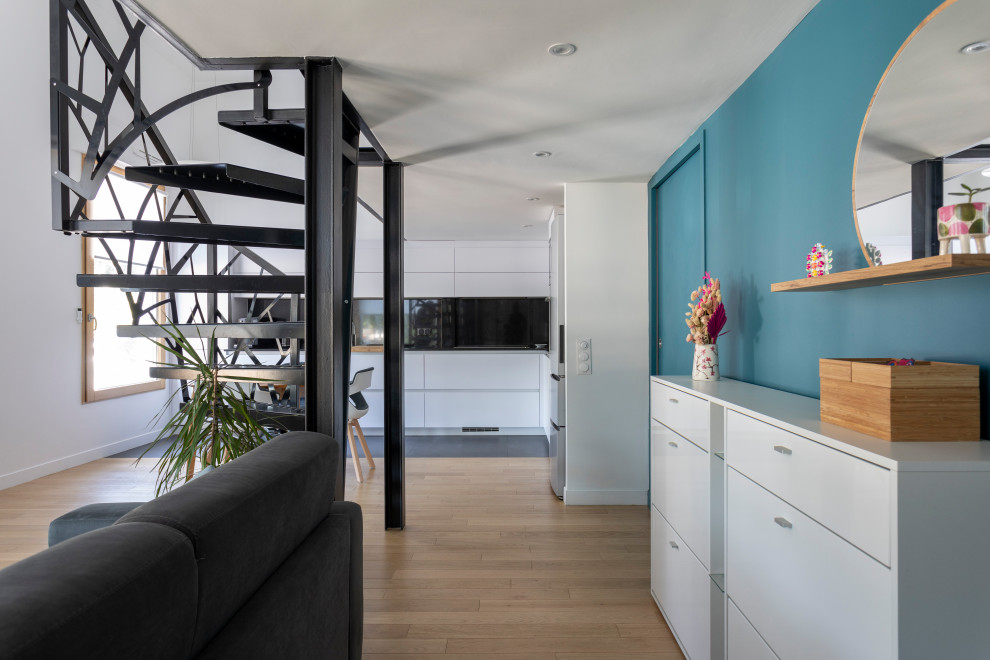 Inspiration för små moderna hallar, med blå väggar, ljust trägolv, en enkeldörr, en vit dörr och brunt golv