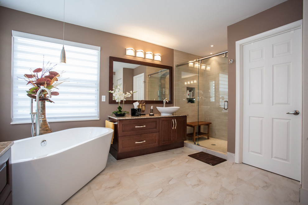 Design ideas for a traditional bathroom in Miami with a vessel sink, raised-panel cabinets, medium wood cabinets, granite benchtops, a freestanding tub, a curbless shower, a one-piece toilet, multi-coloured tile and porcelain tile.
