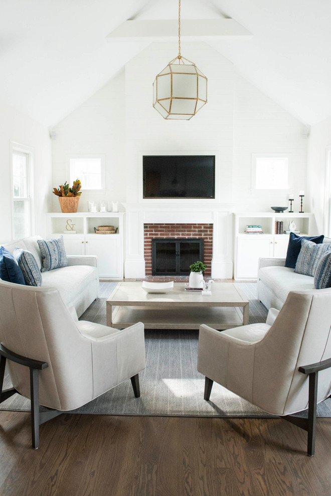 Photo of a transitional living room in Boston with white walls, medium hardwood floors, a standard fireplace, a brick fireplace surround, a wall-mounted tv and brown floor.