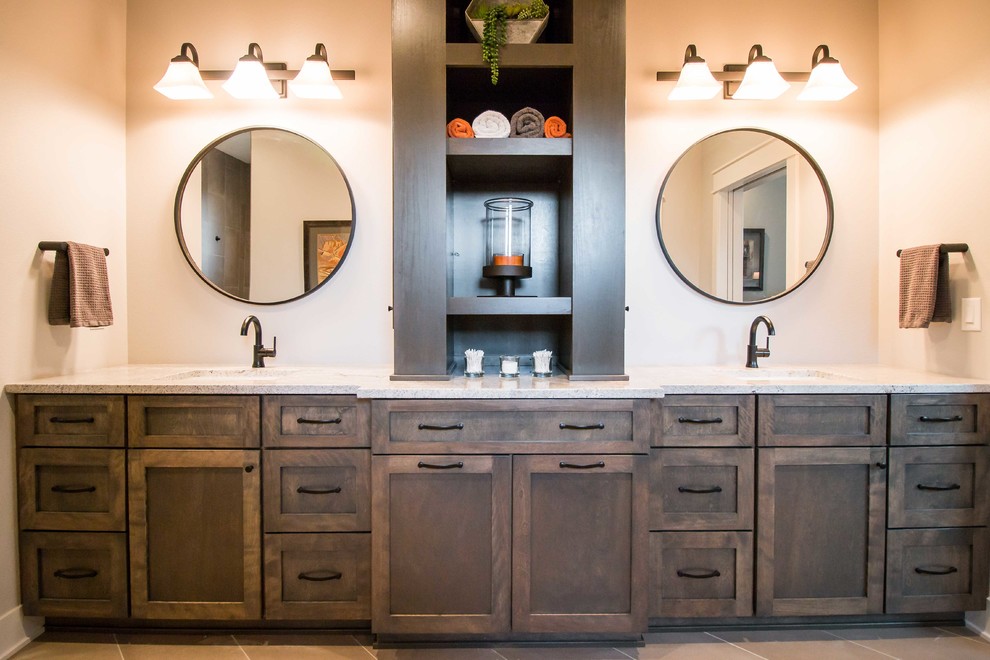 Inspiration for a mid-sized country master bathroom in Other with recessed-panel cabinets, dark wood cabinets, a two-piece toilet, beige walls, porcelain floors, an undermount sink, granite benchtops, grey floor and white benchtops.