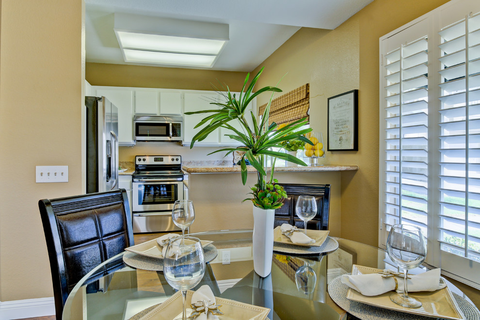Design ideas for a tropical kitchen/dining combo in Orange County with beige walls and dark hardwood floors.