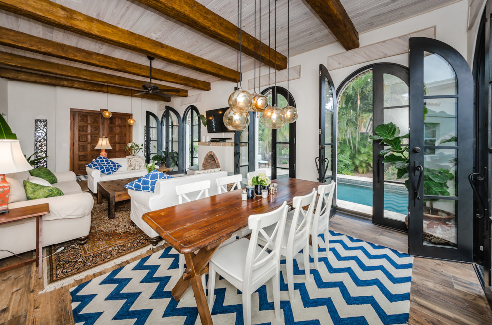Photo of a large eclectic open plan dining in Tampa with white walls, medium hardwood floors, brown floor, a wood stove and a plaster fireplace surround.