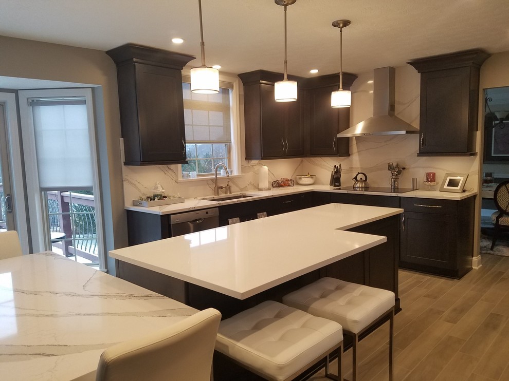 Example of a mid-sized transitional l-shaped porcelain tile and gray floor enclosed kitchen design with an undermount sink, raised-panel cabinets, dark wood cabinets, quartz countertops, white backsplash, stone slab backsplash, stainless steel appliances and an island