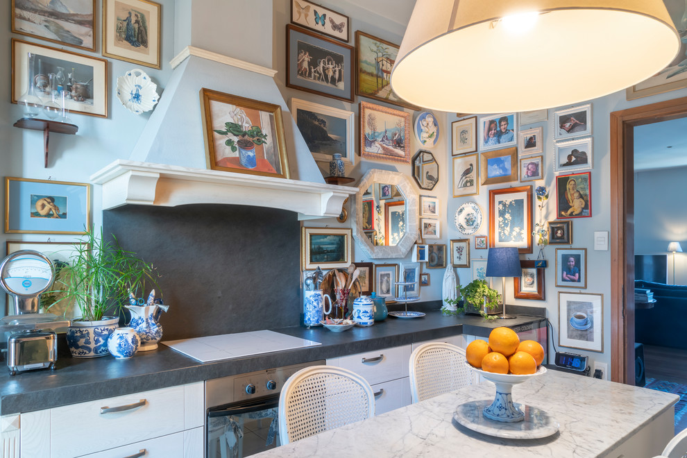 Inspiration for a mid-sized eclectic single-wall separate kitchen in Venice with a drop-in sink, raised-panel cabinets, white cabinets, marble benchtops, multi-coloured splashback, slate splashback, white appliances, porcelain floors, grey floor and black benchtop.