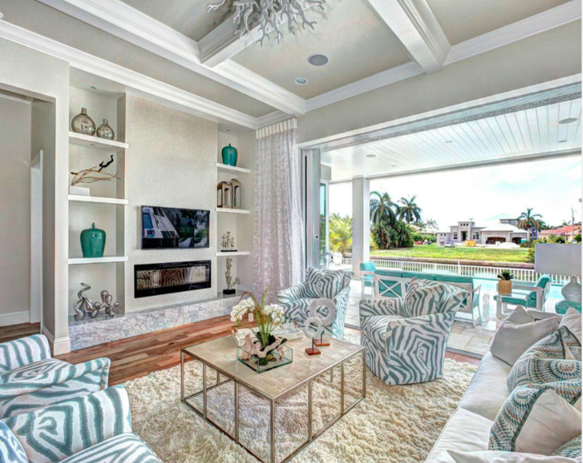 Photo of a large beach style formal open concept living room in Miami with beige walls, medium hardwood floors, a ribbon fireplace, a stone fireplace surround and a wall-mounted tv.