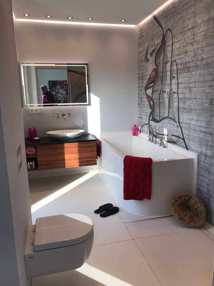 Badezimmer En Suite With Kassettenfronten, hellbraunen Holzschränken, Einbaubadewanne, bodengleicher Dusche, Wandtoilette mit Spülkasten, weißer Wandfarbe, Keramikboden, Aufsatzwaschbecken, Edelstahl-Waschbecken/Waschtisch, weißem Boden, Falttür-Duschabtrennung and schwarzer Waschtischplatte in Cologne