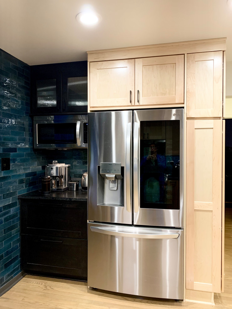 Example of a mid-sized transitional u-shaped light wood floor and brown floor eat-in kitchen design with an undermount sink, shaker cabinets, light wood cabinets, granite countertops, blue backsplash, ceramic backsplash, stainless steel appliances, a peninsula and black countertops
