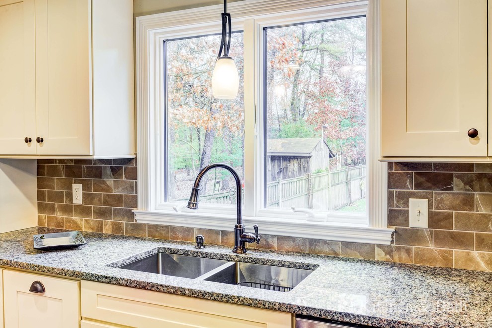 Inspiration for a large transitional u-shaped light wood floor eat-in kitchen remodel in Providence with an undermount sink, shaker cabinets, beige cabinets, granite countertops, brown backsplash, porcelain backsplash, stainless steel appliances and an island