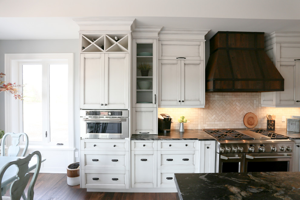 Inspiration for a large rustic l-shaped dark wood floor and brown floor open concept kitchen remodel in Toronto with an undermount sink, recessed-panel cabinets, white cabinets, beige backsplash, glass tile backsplash, stainless steel appliances, an island, onyx countertops and black countertops