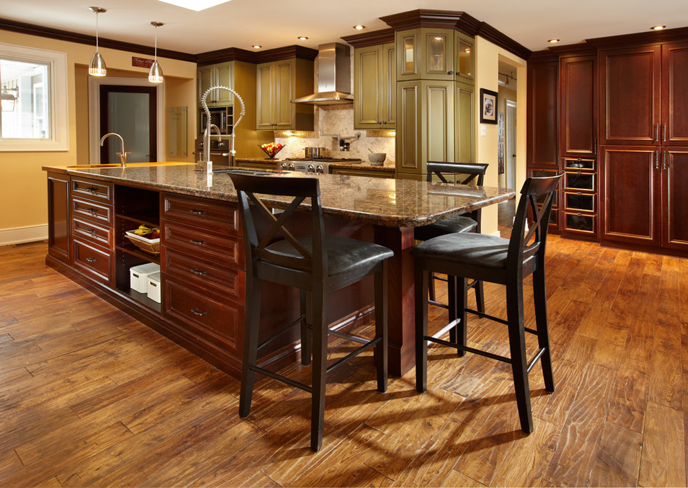 Example of a mid-sized transitional l-shaped light wood floor eat-in kitchen design in Toronto with granite countertops, beige backsplash, stone tile backsplash, stainless steel appliances, an island, an undermount sink, recessed-panel cabinets and green cabinets