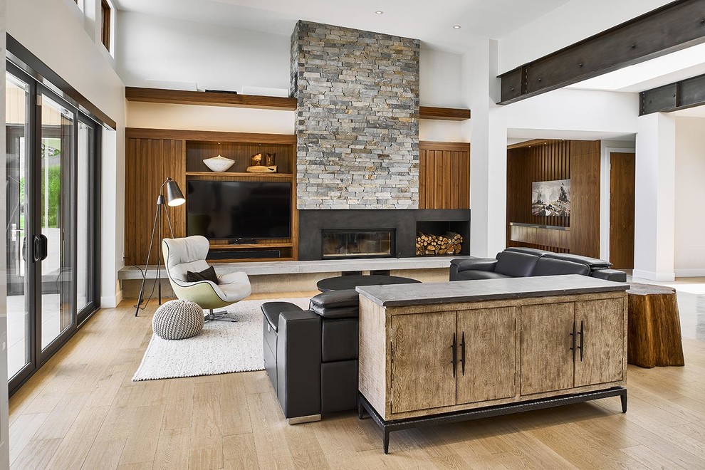 Inspiration for a large contemporary open concept living room in Other with a standard fireplace, a stone fireplace surround, white walls, light hardwood floors, a concealed tv and beige floor.