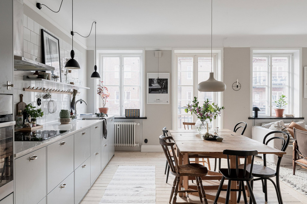 Mid-sized scandinavian single-wall open plan kitchen in Malmo with flat-panel cabinets, grey cabinets, light hardwood floors, white benchtop, an undermount sink and beige floor.