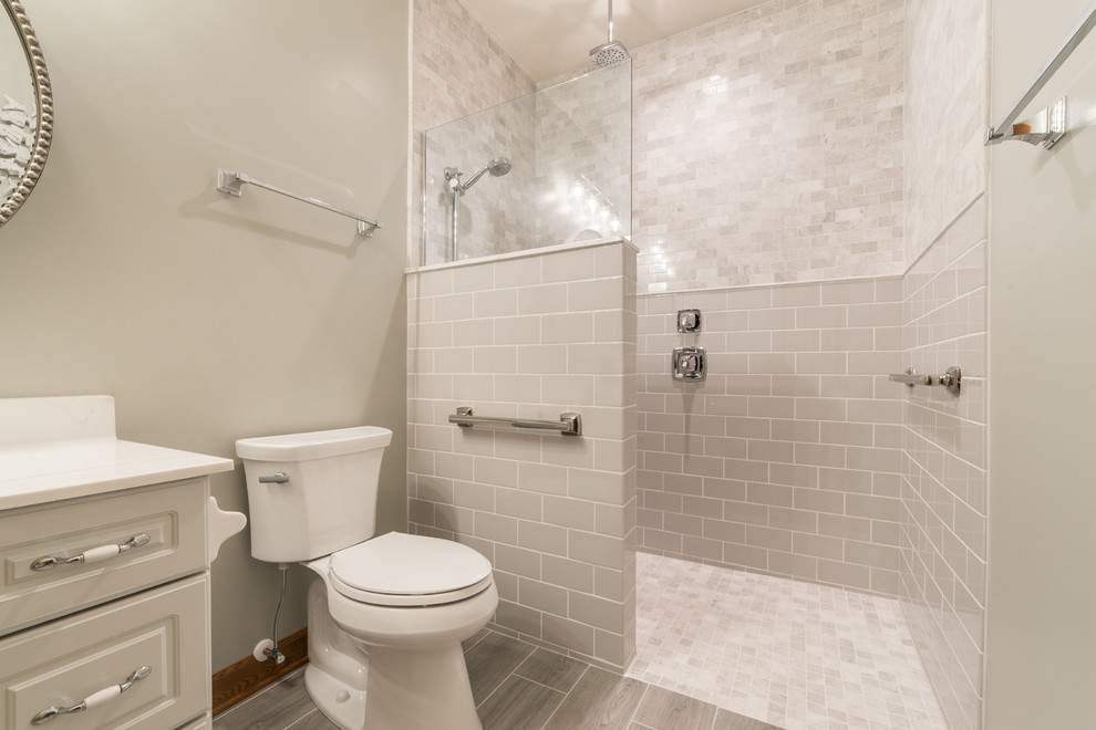 Mid-sized traditional 3/4 bathroom in Chicago with shaker cabinets, grey cabinets, a curbless shower, a two-piece toilet, ceramic tile, grey walls, ceramic floors, an integrated sink, marble benchtops, grey floor, an open shower and white benchtops.