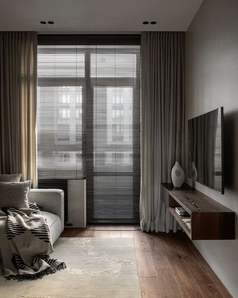 Стильный дизайн: серо-белая гостиная комната среднего размера в современном стиле с черными стенами, паркетным полом среднего тона, телевизором на стене, зоной отдыха и ковром на полу - последний тренд