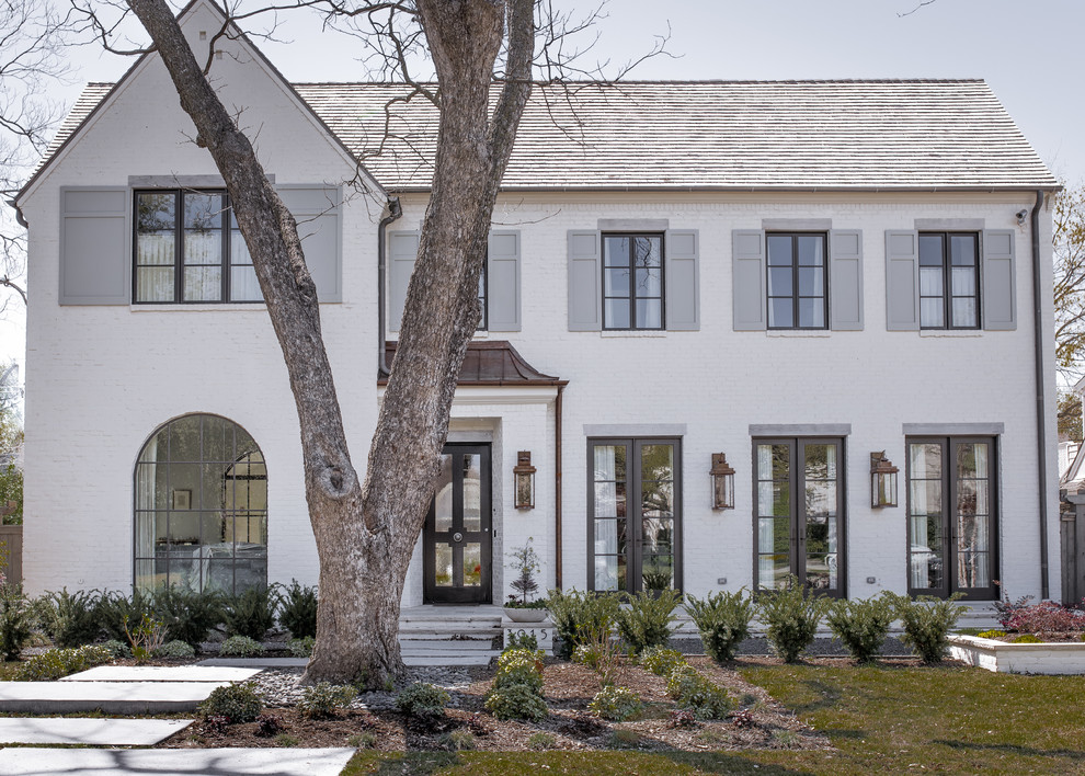 Large transitional two-storey brick white house exterior in Dallas with a gable roof and a shingle roof.