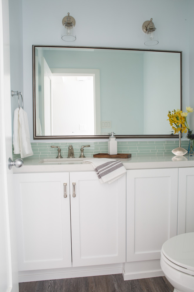 Design ideas for a small beach style powder room in Los Angeles with a one-piece toilet, green tile, vinyl floors, an undermount sink, engineered quartz benchtops, glass tile and recessed-panel cabinets.