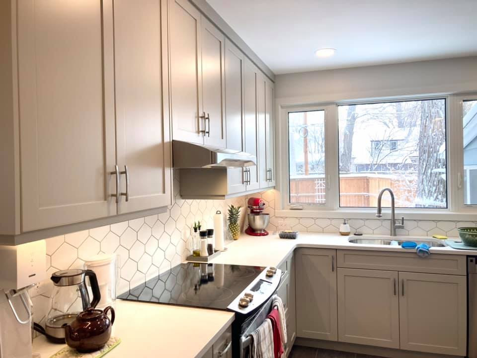 Inspiration for a mid-sized transitional u-shaped vinyl floor and gray floor enclosed kitchen remodel with an undermount sink, shaker cabinets, beige cabinets, quartz countertops, white backsplash, ceramic backsplash, stainless steel appliances and white countertops