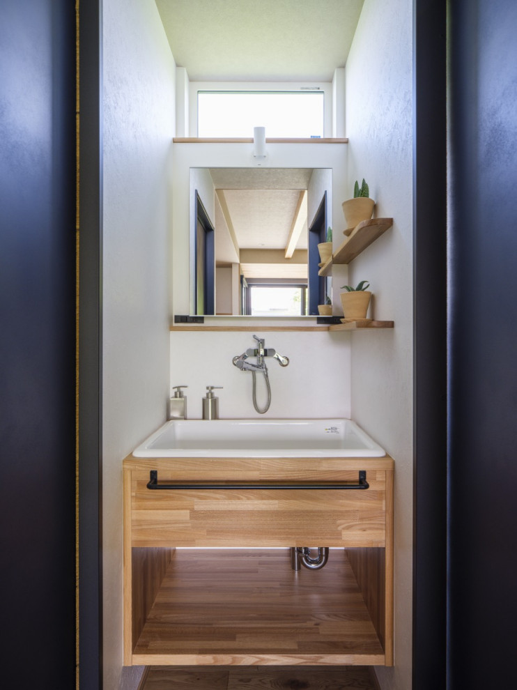 Inspiration för mellanstora moderna brunt toaletter, med vita skåp, vita väggar, ljust trägolv, bänkskiva i glas och beiget golv