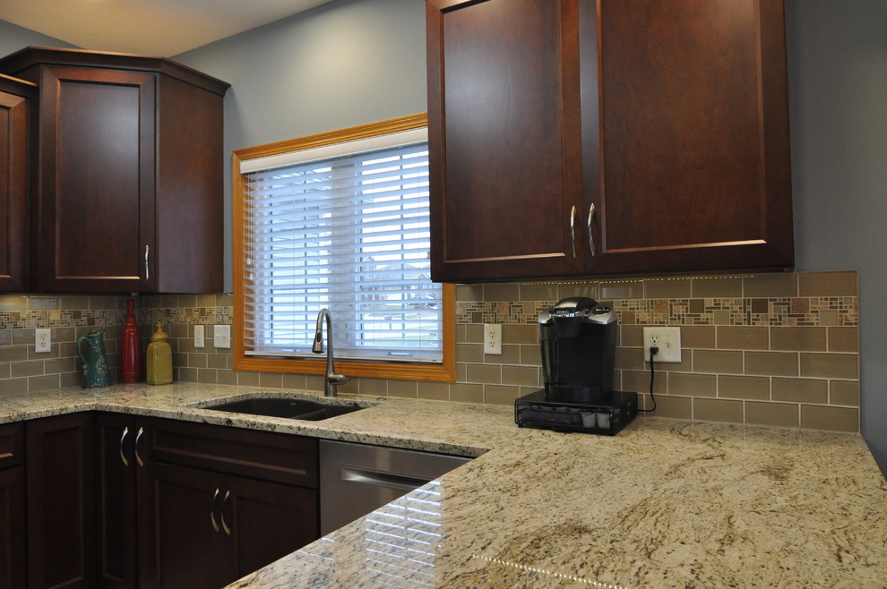 Mid-sized transitional u-shaped porcelain tile eat-in kitchen photo with an undermount sink, recessed-panel cabinets, dark wood cabinets, granite countertops, beige backsplash and stainless steel appliances