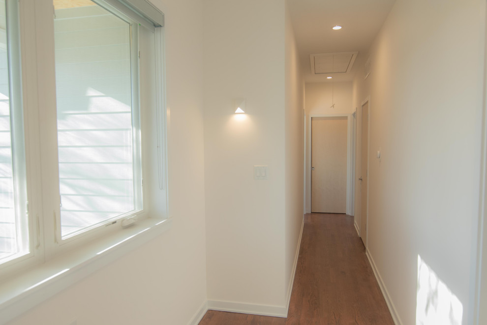 Photo of a contemporary hallway in Chicago with beige walls, light hardwood floors and brown floor.