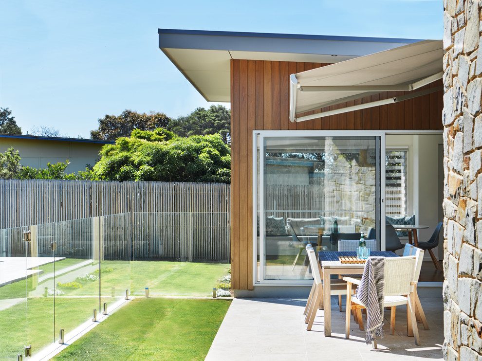 Design ideas for a mid-sized contemporary backyard patio in Melbourne with concrete pavers and an awning.