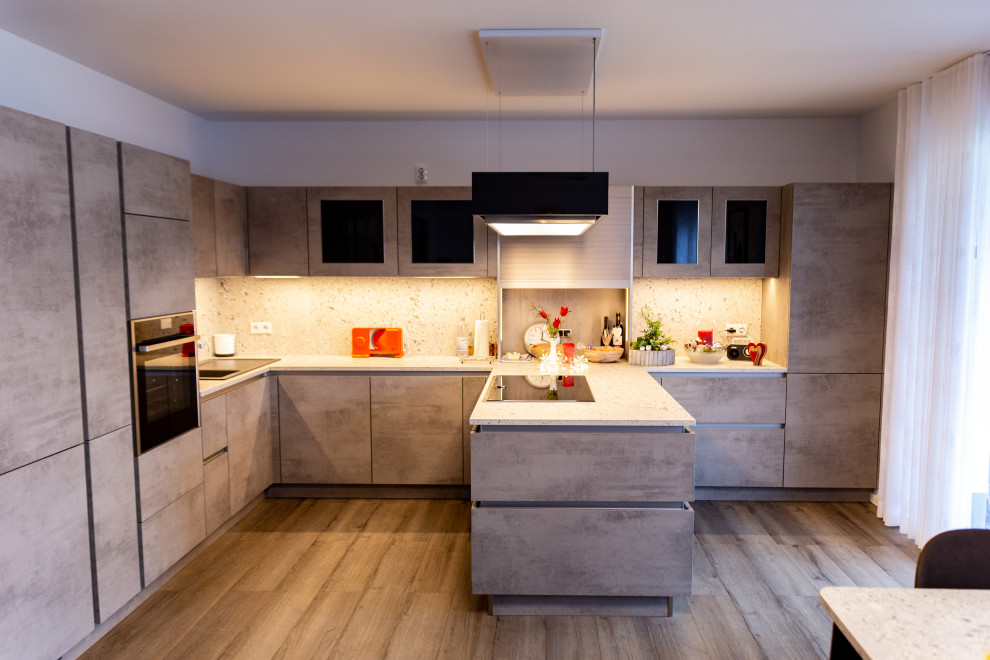 Küche in U-Form mit Einbauwaschbecken, Glasfronten, grauen Schränken, Arbeitsplatte aus Holz, Küchenrückwand in Grau, Rückwand aus Holz, schwarzen Elektrogeräten, Keramikboden, Halbinsel, braunem Boden, grauer Arbeitsplatte und Tapetendecke in Dusseldorf