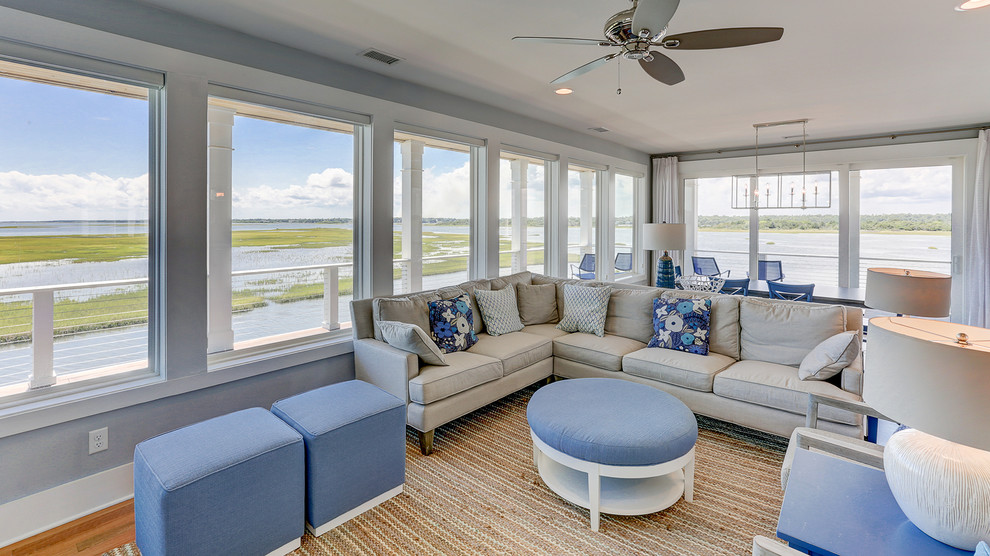 This is an example of a beach style living room in Other with blue walls and light hardwood floors.