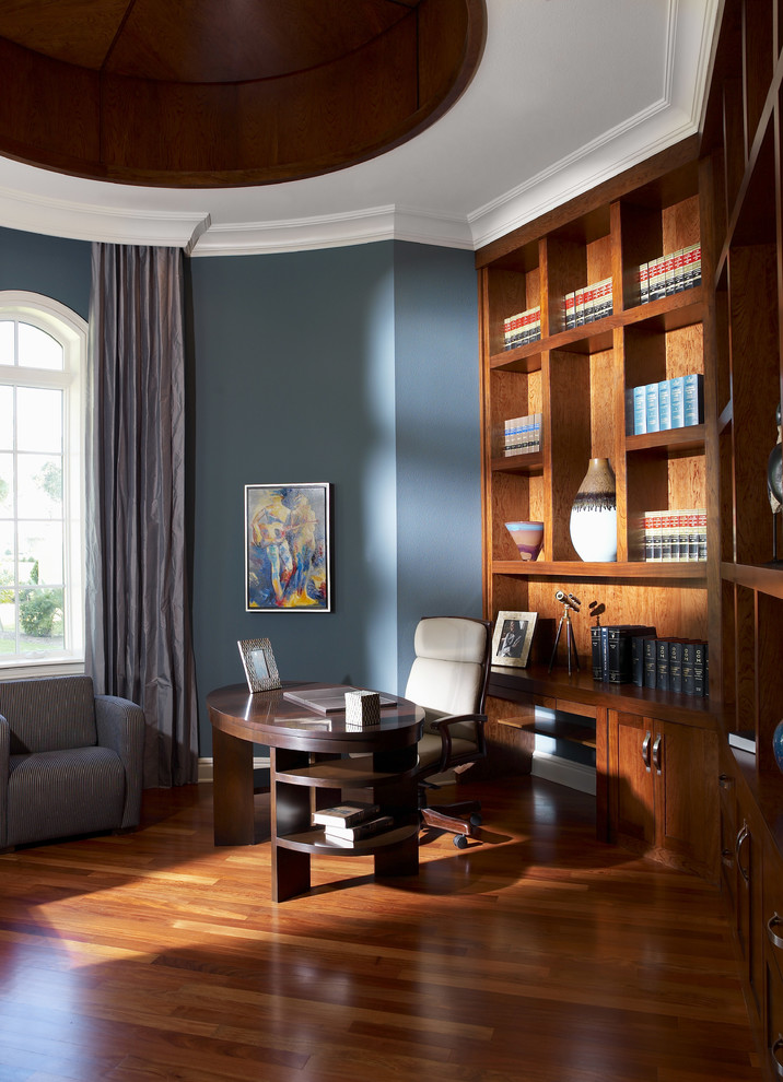 Design ideas for a large contemporary home office in Tampa with a library, blue walls, dark hardwood floors, no fireplace, a freestanding desk and brown floor.