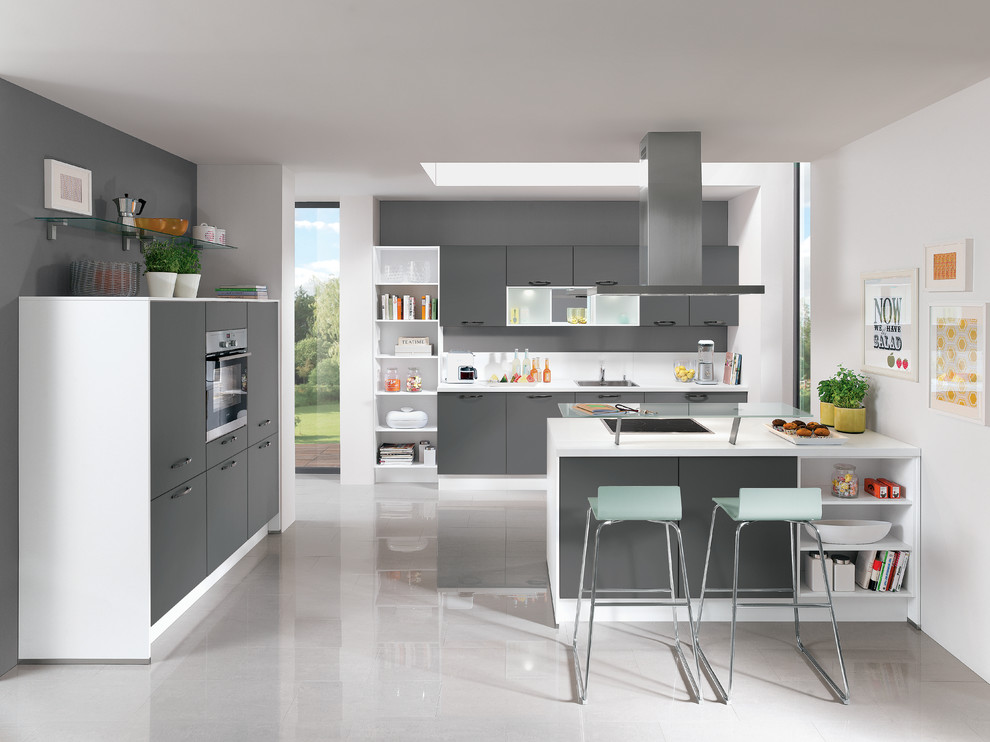 Large contemporary u-shaped open plan kitchen in Hamburg with an integrated sink, flat-panel cabinets, beige cabinets, wood benchtops, beige splashback, glass sheet splashback, stainless steel appliances, cement tiles, a peninsula and grey floor.