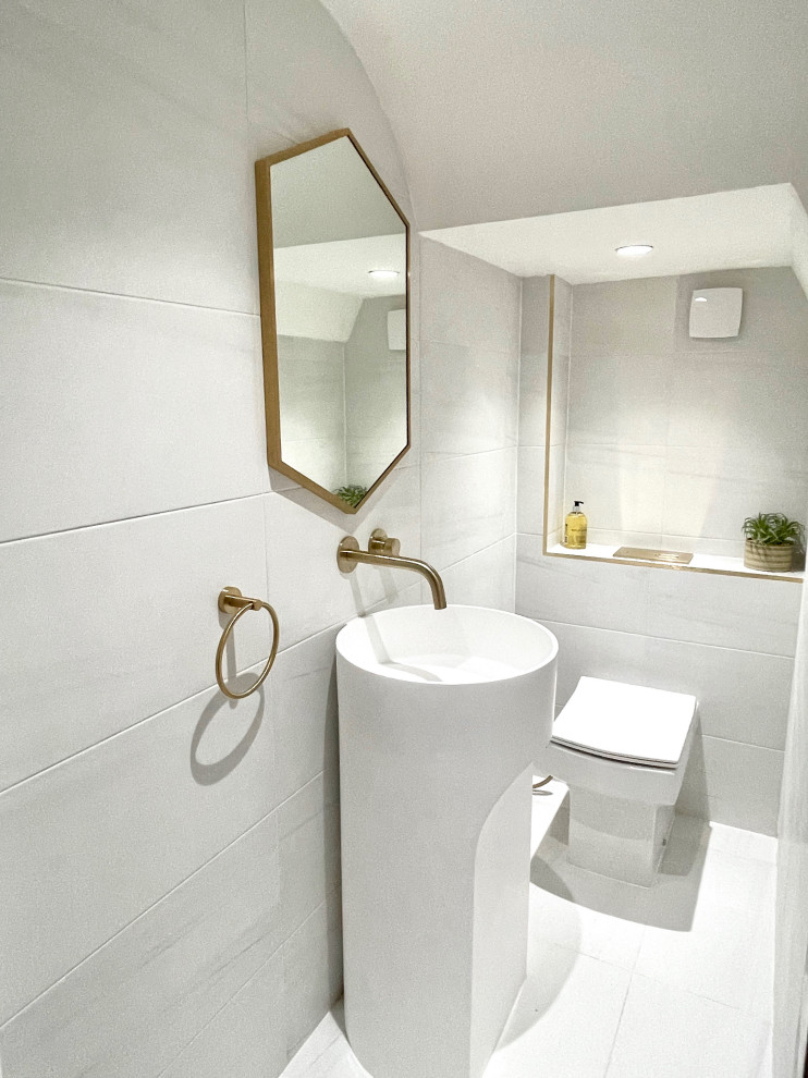 Cette image montre un petit WC et toilettes minimaliste avec des portes de placard blanches, WC à poser, un carrelage blanc, des carreaux de porcelaine et meuble-lavabo sur pied.