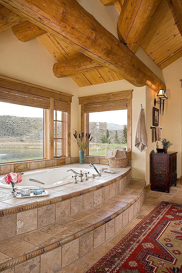 This is an example of a large country master bathroom in Other with a hot tub, beige tile and stone tile.