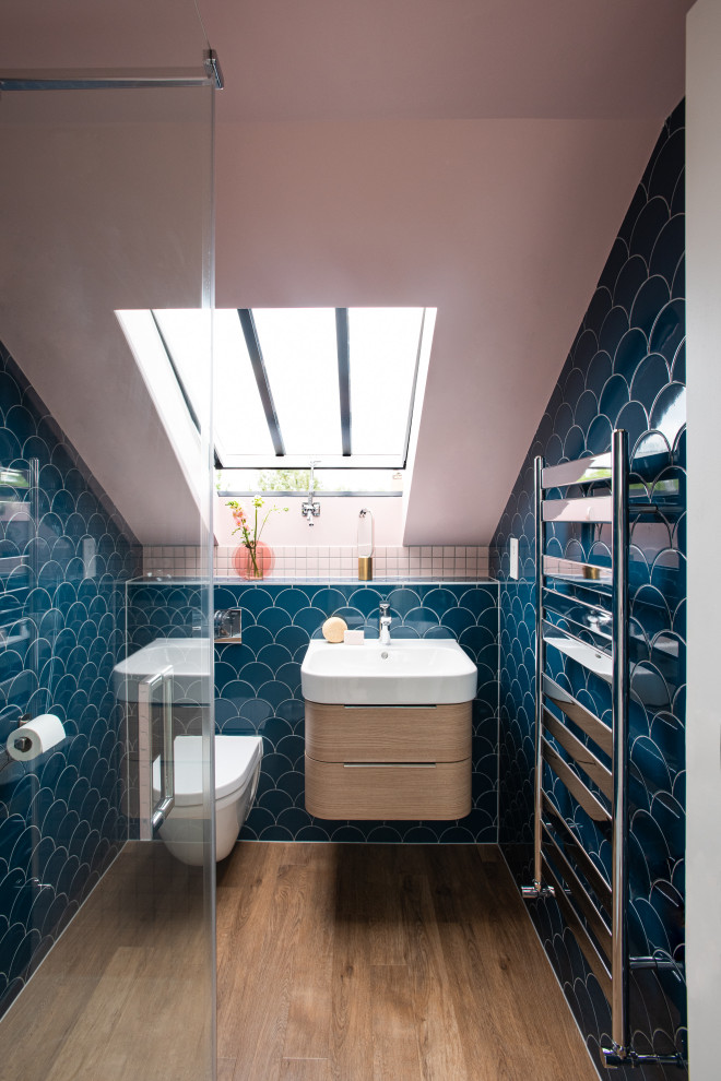 Inspiration for a small transitional 3/4 bathroom in London with flat-panel cabinets, brown cabinets, an open shower, a wall-mount toilet, blue tile, ceramic tile, pink walls, light hardwood floors, a wall-mount sink, brown floor, a hinged shower door, a single vanity and a floating vanity.