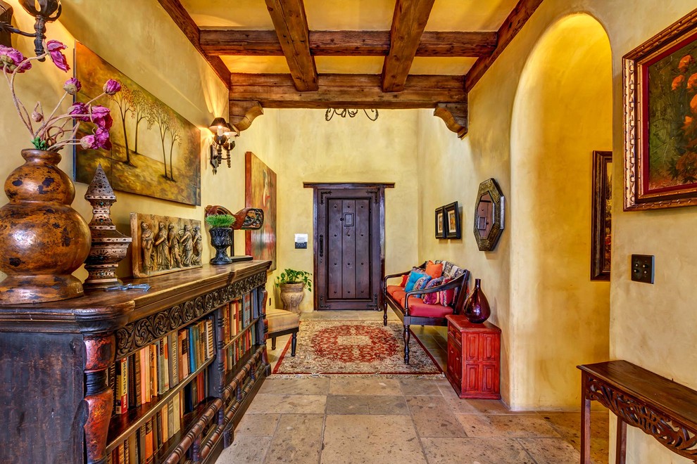 This is an example of an entry hall in San Diego with yellow walls, slate floors, a single front door, a dark wood front door and beige floor.