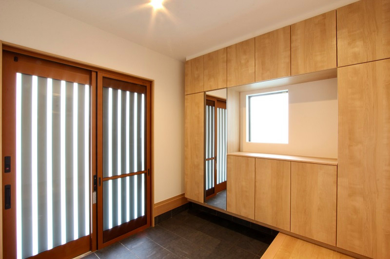 На фото: узкая прихожая среднего размера с белыми стенами, полом из керамической плитки, раздвижной входной дверью, коричневой входной дверью, серым полом, потолком с обоями и обоями на стенах с