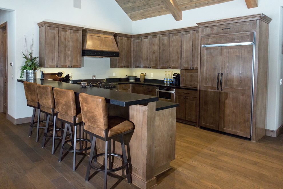 Example of a large mountain style u-shaped medium tone wood floor and brown floor open concept kitchen design in Phoenix with an undermount sink, shaker cabinets, medium tone wood cabinets, solid surface countertops, paneled appliances, no island and black countertops