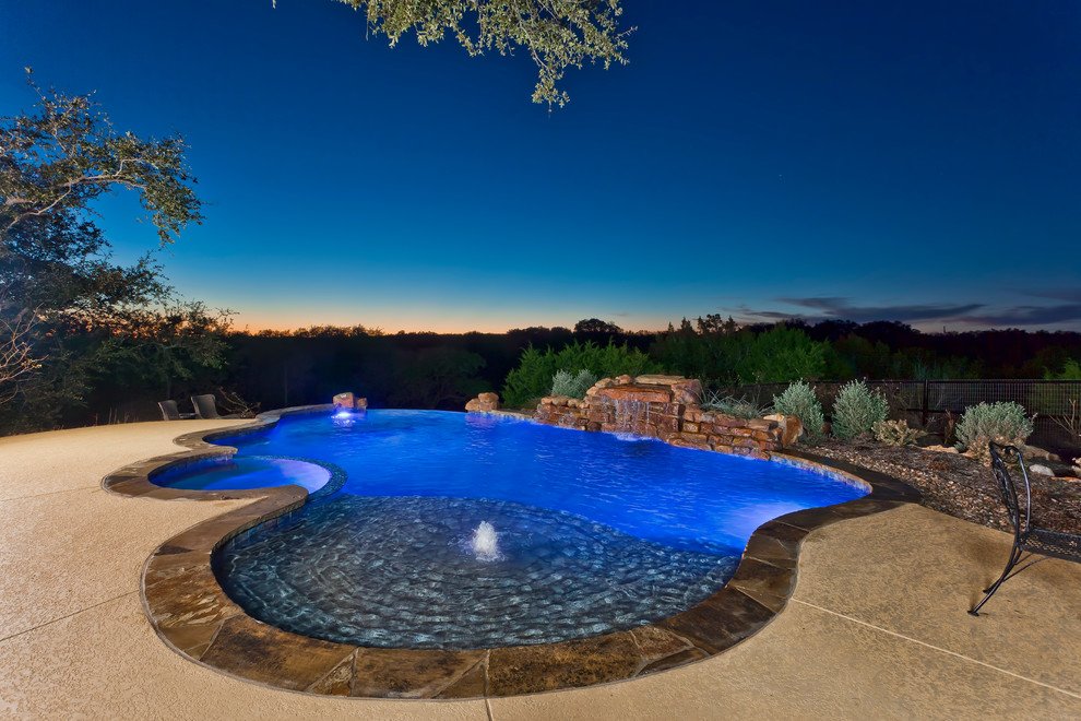Large transitional backyard custom-shaped pool in Other with a hot tub and stamped concrete.