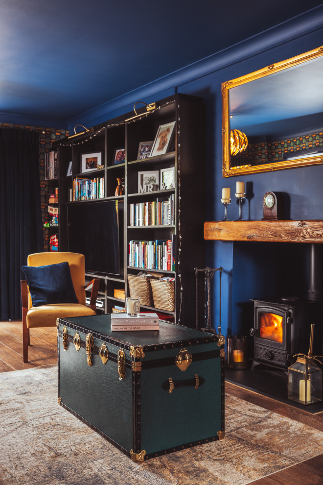 Modelo de salón con rincón musical cerrado contemporáneo de tamaño medio con paredes azules, suelo vinílico, estufa de leña, marco de chimenea de madera, pared multimedia, suelo marrón y papel pintado