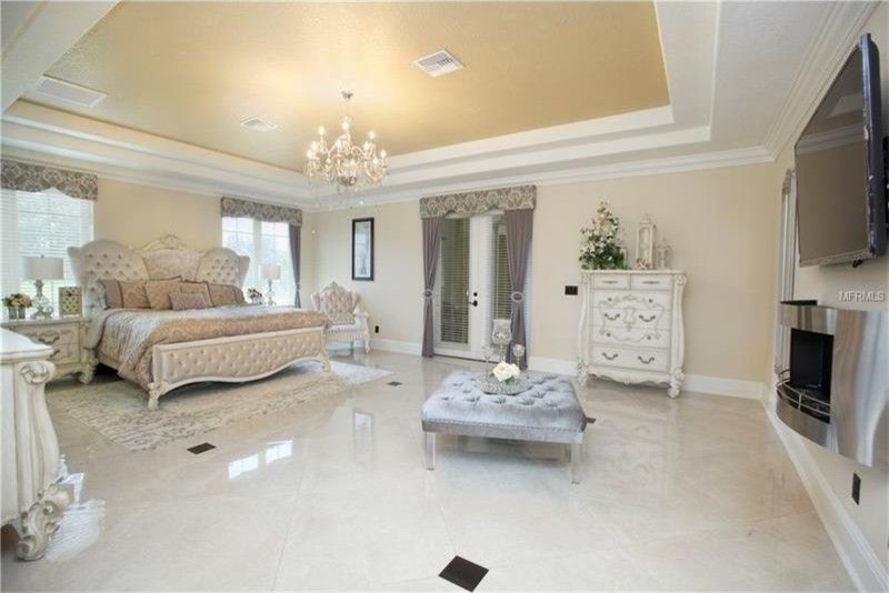 Large mediterranean master bedroom in Orlando with beige walls, marble floors, a ribbon fireplace, a metal fireplace surround and beige floor.