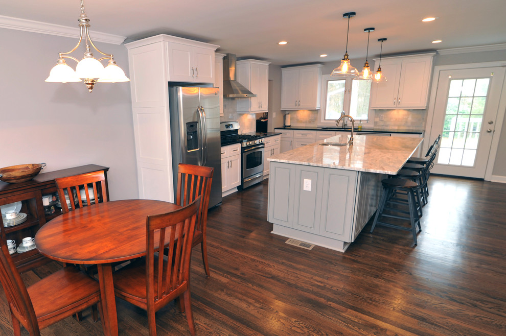 Example of a mid-sized transitional l-shaped medium tone wood floor open concept kitchen design in Atlanta with a double-bowl sink, white cabinets, quartzite countertops, white backsplash, stainless steel appliances and an island