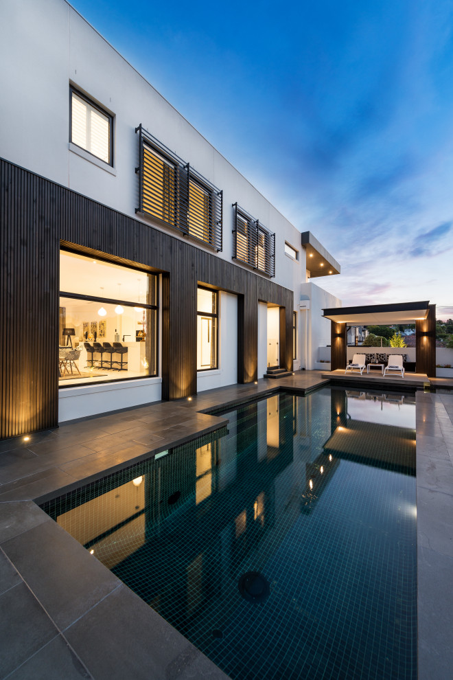 Inspiration for a large contemporary backyard custom-shaped pool in Melbourne with concrete pavers.