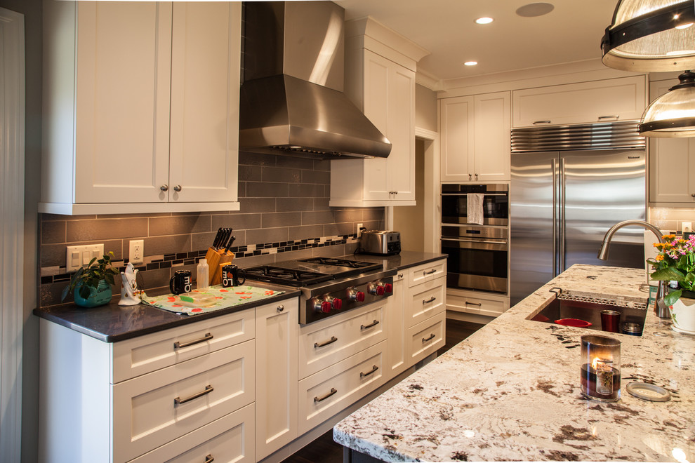 Inspiration for a transitional dark wood floor and brown floor open concept kitchen remodel with an undermount sink, shaker cabinets, white cabinets, granite countertops, beige backsplash, subway tile backsplash, stainless steel appliances and an island