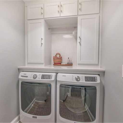 Photo of a small transitional galley laundry cupboard in DC Metro with recessed-panel cabinets, white cabinets, quartz benchtops, engineered quartz splashback and a side-by-side washer and dryer.