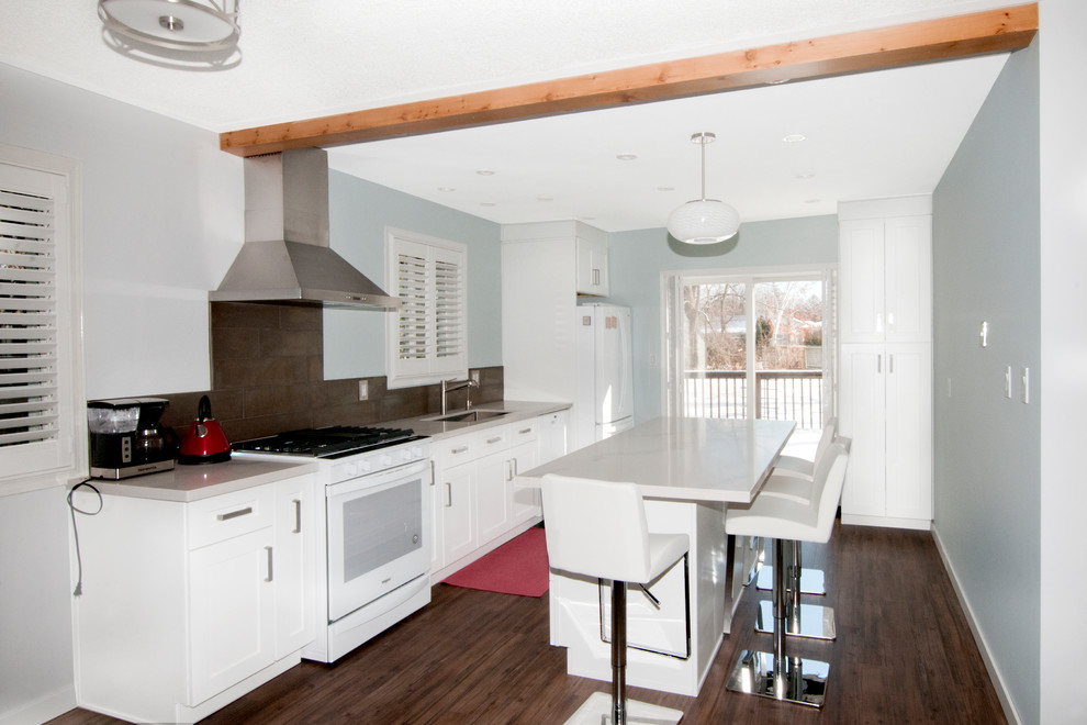 Example of a mid-sized transitional kitchen design in Toronto with an undermount sink, shaker cabinets, white cabinets, quartz countertops, metallic backsplash, ceramic backsplash, white appliances, an island and white countertops