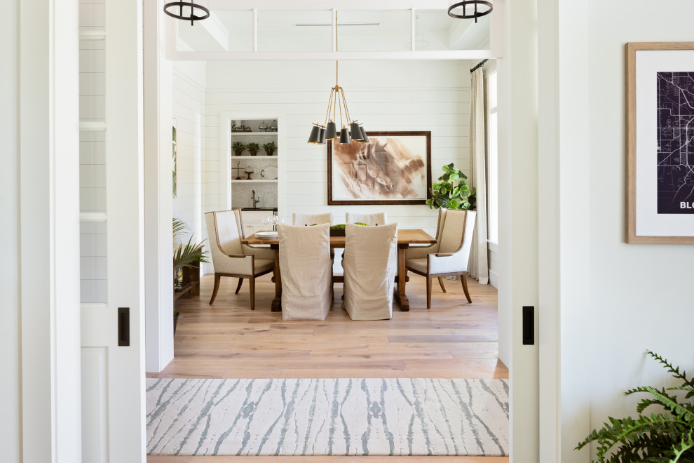 Immagine di una sala da pranzo aperta verso la cucina stile marino con pareti bianche, parquet chiaro, pavimento marrone e pareti in perlinato