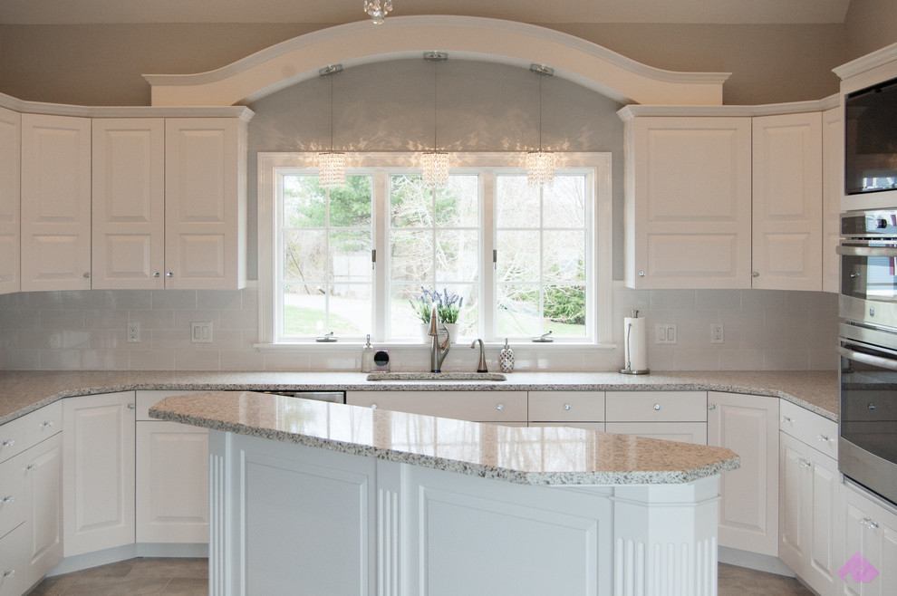 Inspiration for a mid-sized transitional u-shaped kitchen remodel in Boston with an undermount sink, raised-panel cabinets, white cabinets, granite countertops, stainless steel appliances and an island